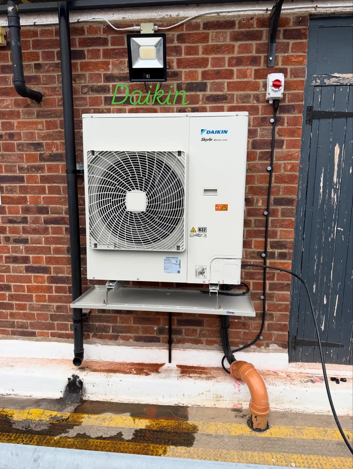 Daikin AC condenser mounted neatly on a brick wall